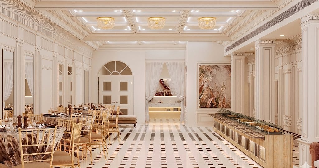 The dining side of the banquet hall, gold-chiavari chairs and round tables beside a long warm-wood buffet and live-counter station under crystal chandeliers
