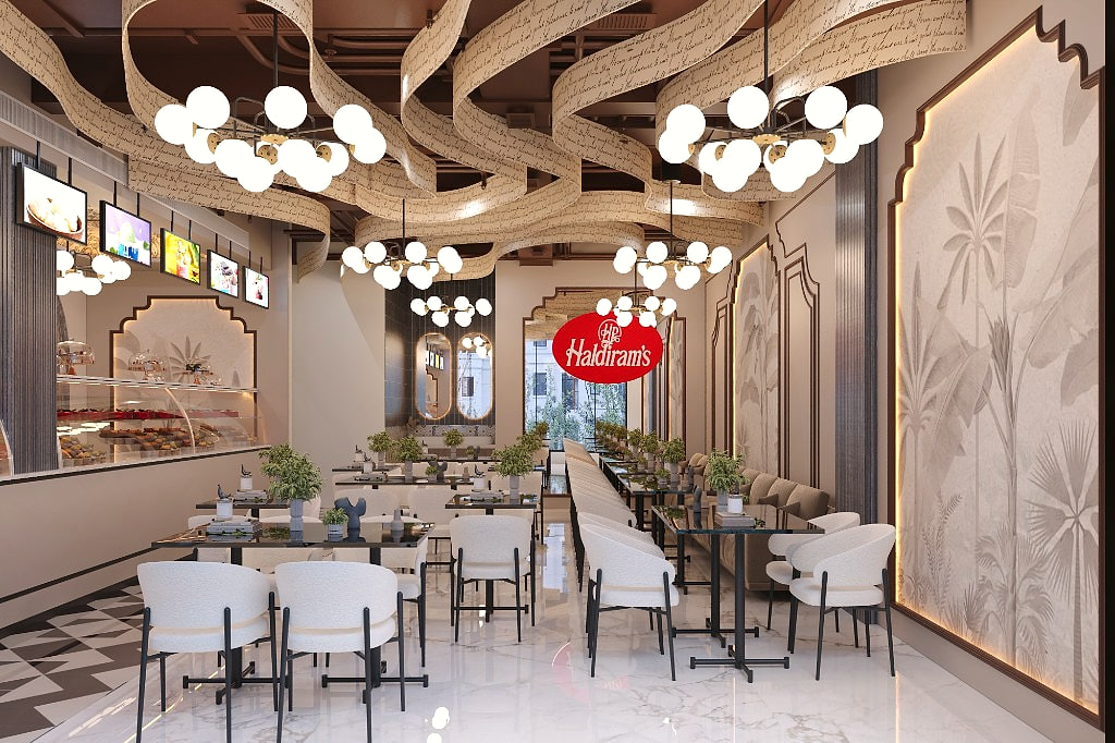 Dining area with the Haldiram's mark suspended below cluster chandeliers and ribbon ceiling