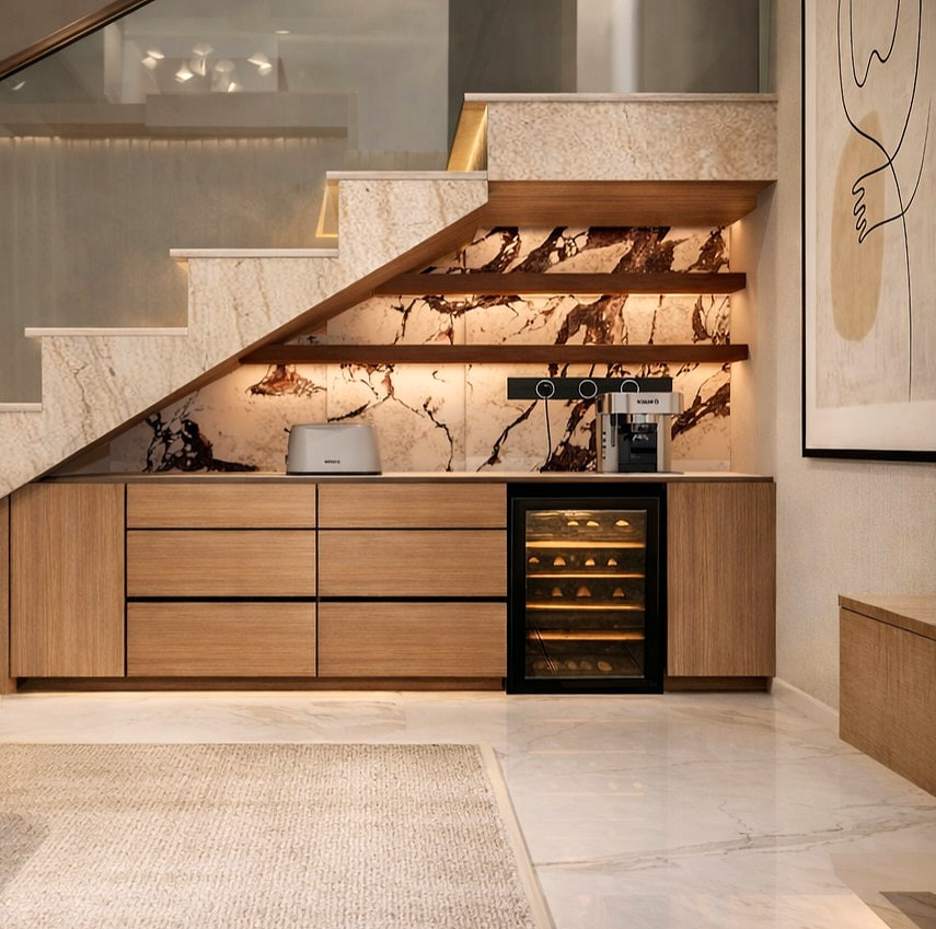 Close-up of the under-stair bar with bookmatched stone backing, oak cabinetry and a built-in wine fridge