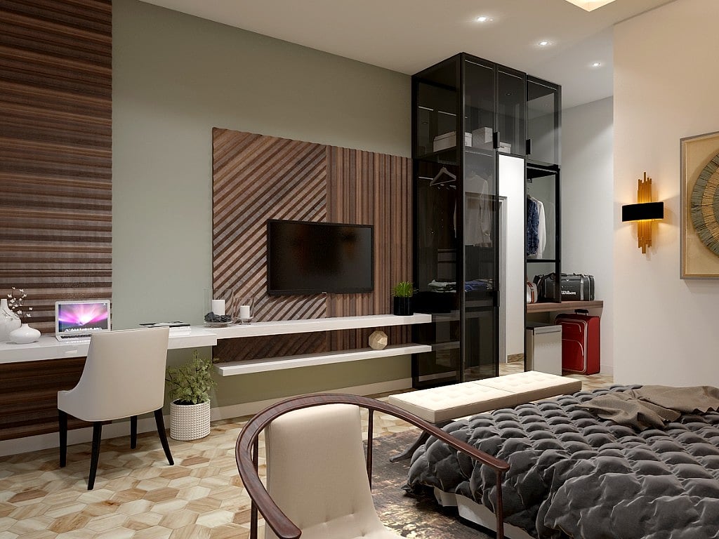 A guest room working wall with a wood-veneered and sage panel carrying the television, a floating white desk, a glass-fronted wardrobe and a framed mandala artwork lit by brass sconces