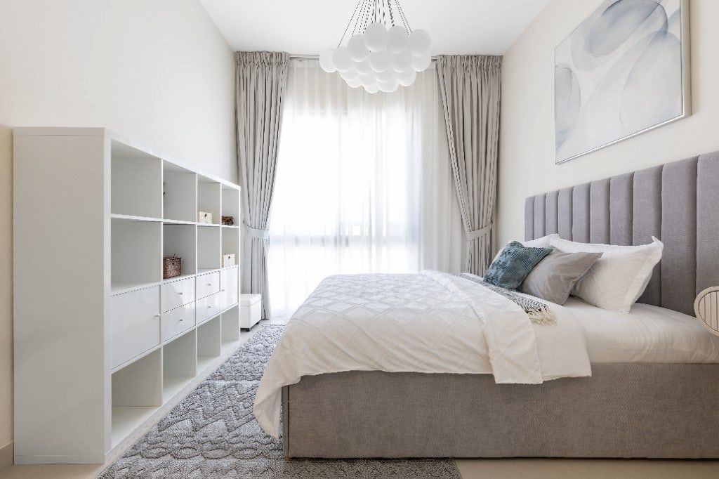 Second bedroom with a grey channel-tufted headboard, a white modular bookcase and a cluster-ball pendant above the bed