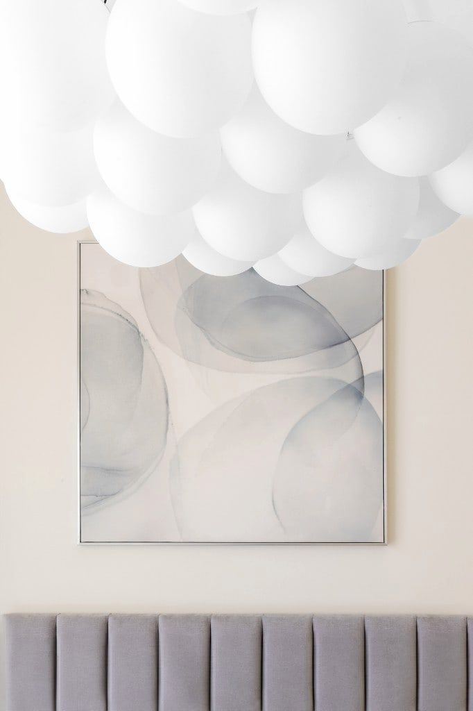 Master bedroom detail, frosted-bubble cluster pendant above a grey watercolour canvas and a channel-tufted grey velvet headboard