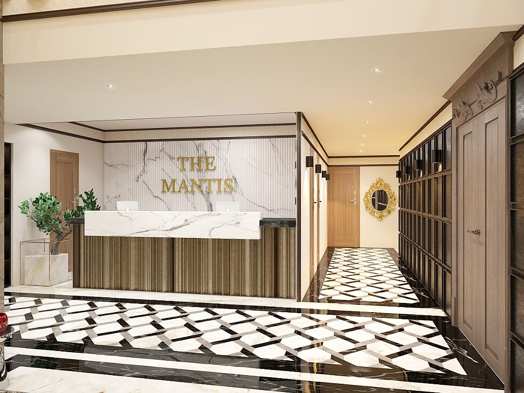 The Mantis reception, the hotel name in brushed gold above a fluted marble desk, a graphic black-and-white stone floor, panelled timber walls and a gilded mirror