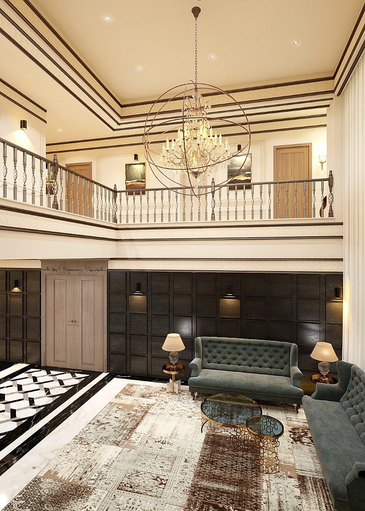The double-height lobby seen toward the mezzanine, a dark coffered panelled wall with sconces, teal settees and gold tables beneath an orb chandelier and a balustraded gallery