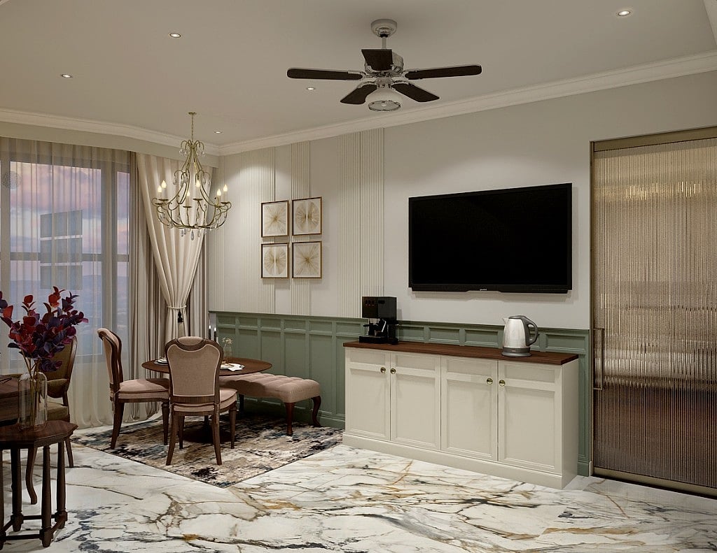 A suite dining and pantry corner, a cream sideboard with a coffee-and-kettle station beside a round table and chairs, sage wainscoting and a crystal chandelier on a book-matched marble floor