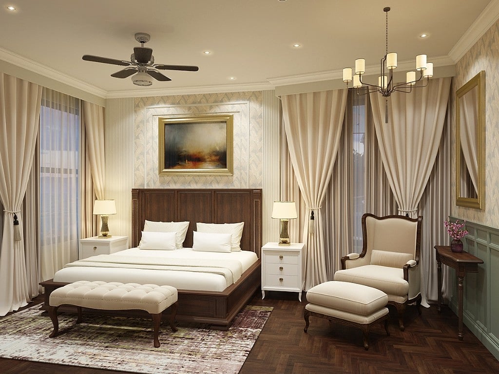 A guest suite at The Mantis with a dark panelled-wood bed, twin gold bedside lamps, a gilded seascape, a cream wingback chair and ottoman and herringbone parquet