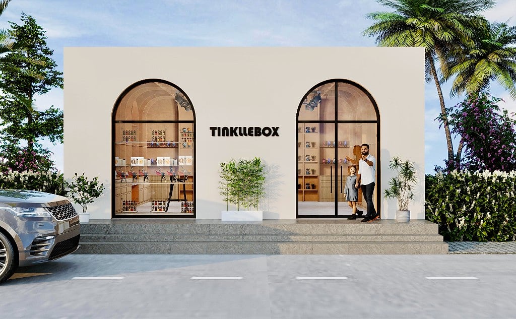 The TinklleBox shopfront by day, a cream box with two arched black-framed display windows and the black wordmark, on a paved forecourt
