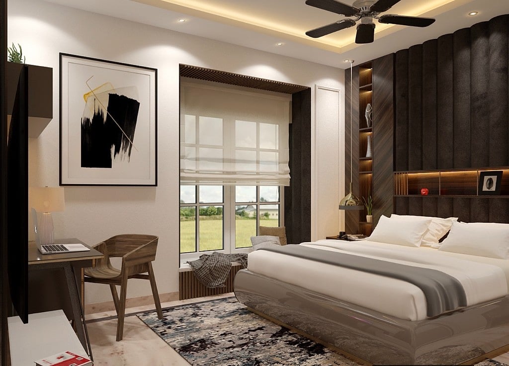 A bedroom with a charcoal channel-panelled headboard wall and backlit niche, a white bed, a grid window with a roman shade looking onto open fields and a wood desk and chair