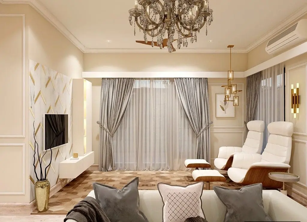 The classic living room with panelled walls, a crystal chandelier, grey drapery, white leather recliners and a marble-and-gold television wall