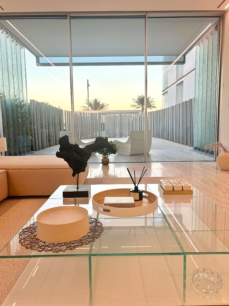 Wide living-room view at sunset, sand-linen sectional beneath an unbroken cove of warm light