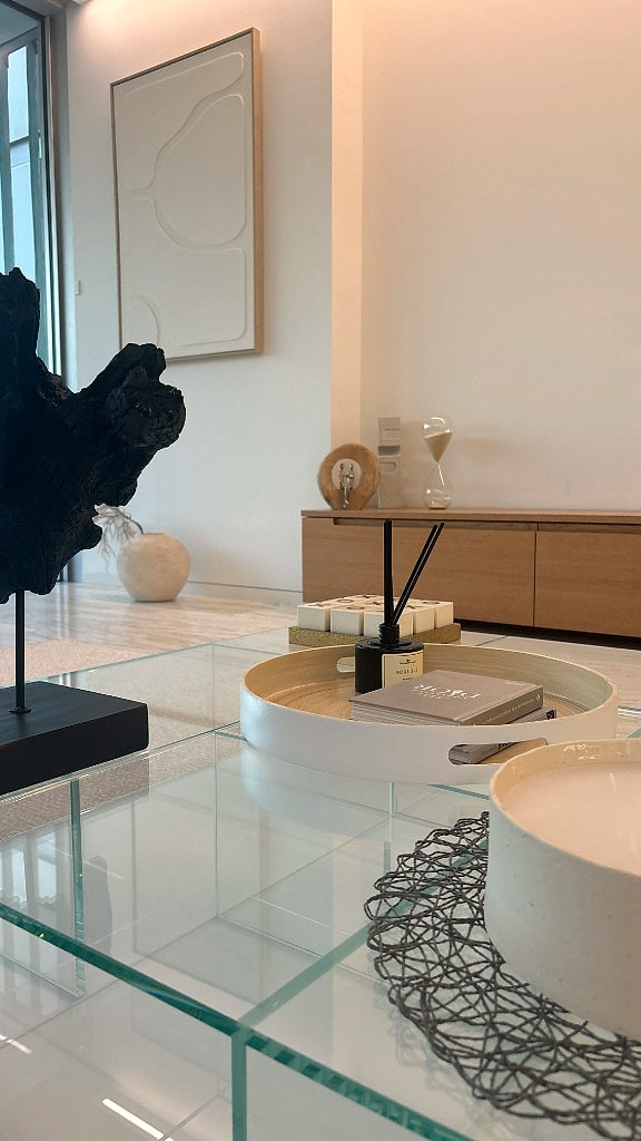 Glass coffee table detail with light oak credenza and plaster relief artwork