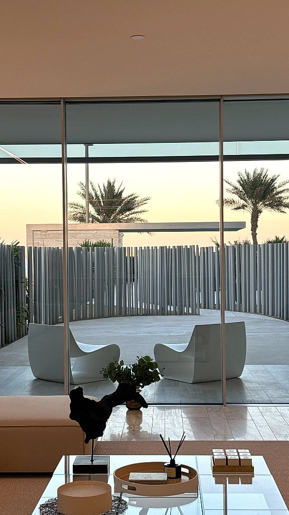 Outdoor lounges seen through floor-to-ceiling glass at golden hour