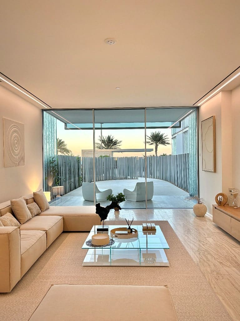 Twilight view across the living room to the cream fluted-stone terrace